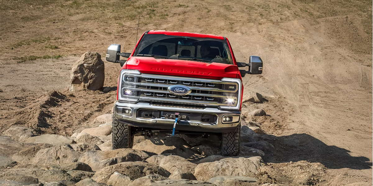 A red 2026 Ford F-150 demonstrating off-road capability on rocky terrain, highlighting durability and performance for outdoor adventures at MSA Ford.